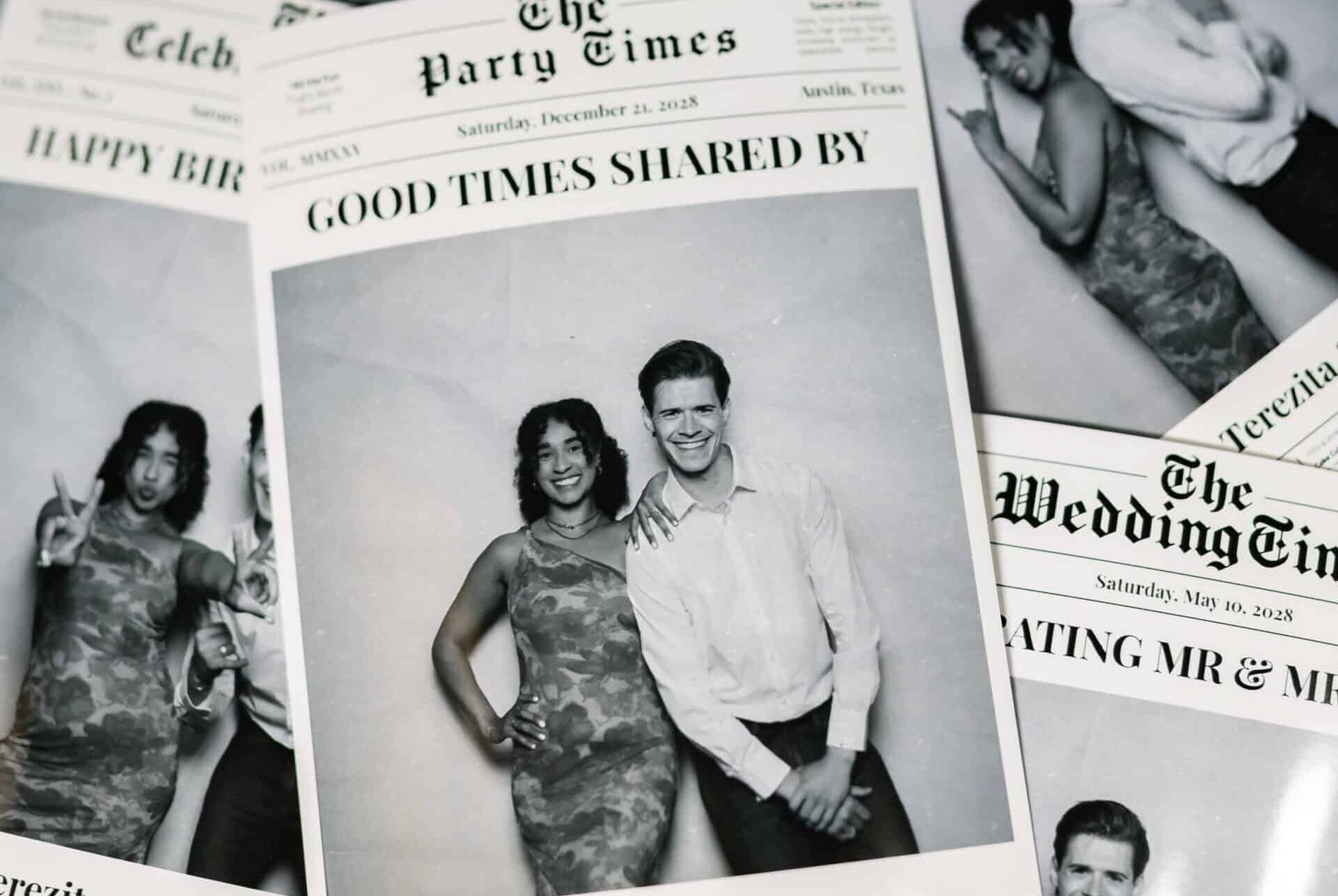 wo people posing in a photo booth, with one wearing sunglasses and a colorful boa, against a custom backdrop with an illuminated frame.