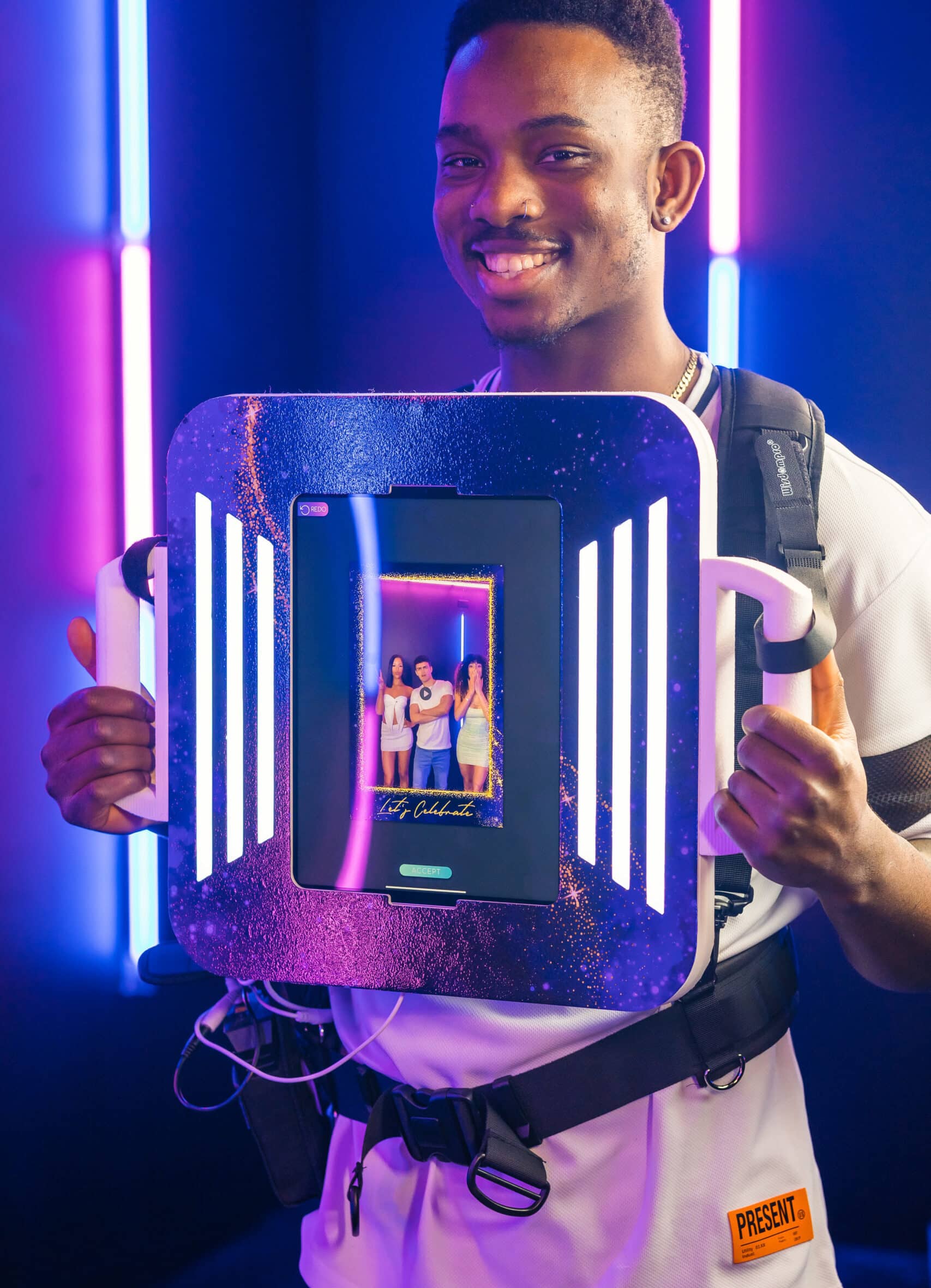 Two women in formal dresses smiling and posing for a picture in a photo booth at an event.