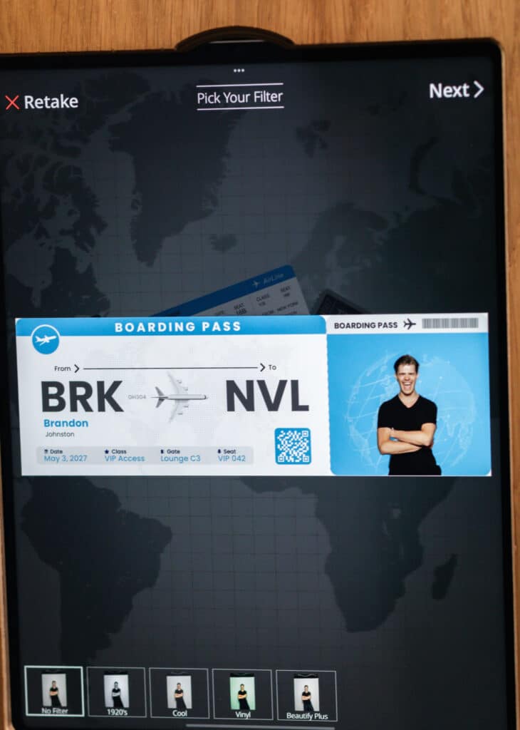 Two women in formal dresses smiling and posing for a picture in a photo booth at an event.