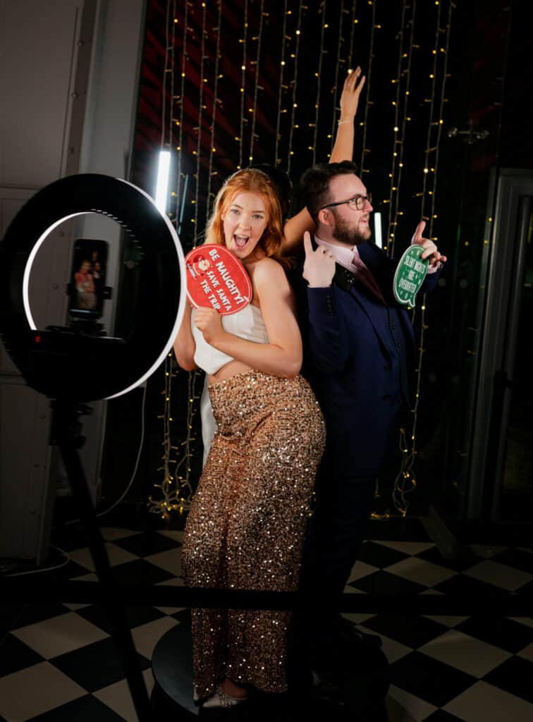 Two women in formal dresses smiling and posing for a picture in a photo booth at an event.