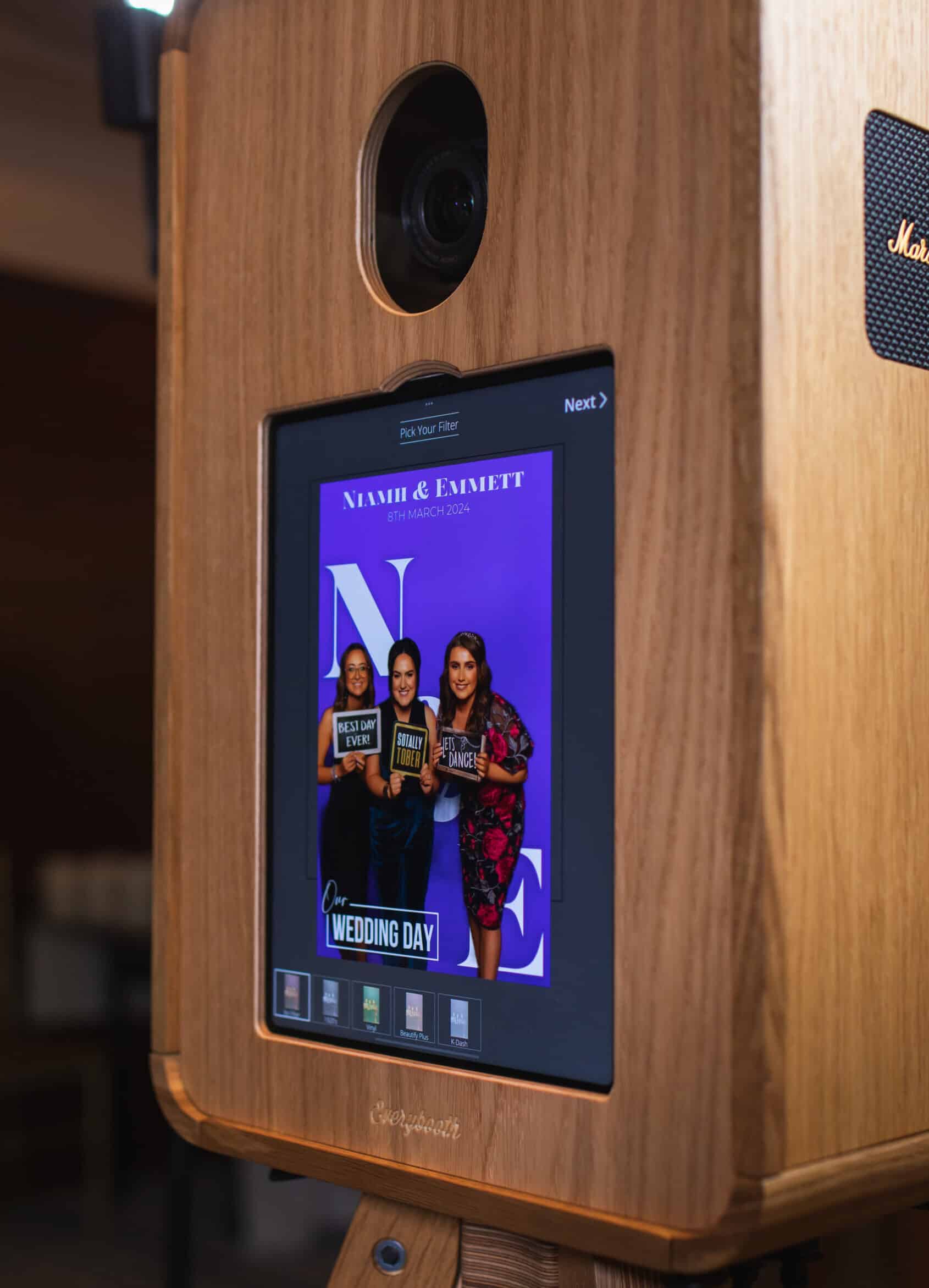 A couple smiling and posing for a picture in a photo booth at their wedding.
