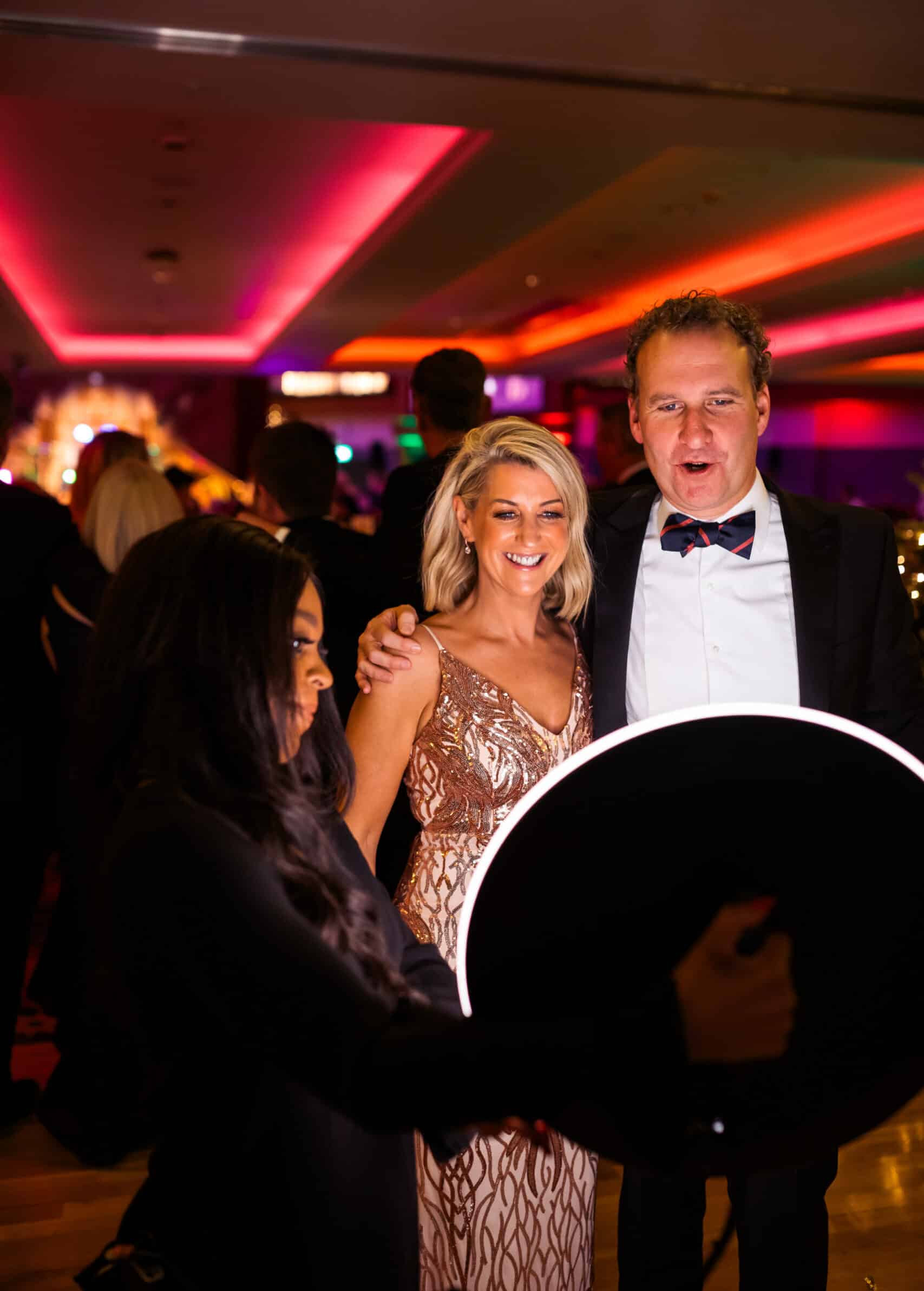 Roamer Booth taking a picture of a couple dressed in tuxedo and gown