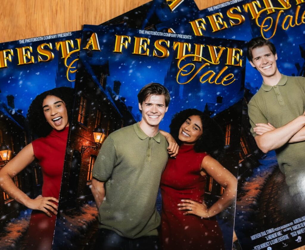 Two women in formal dresses smiling and posing for a picture in a photo booth at an event.