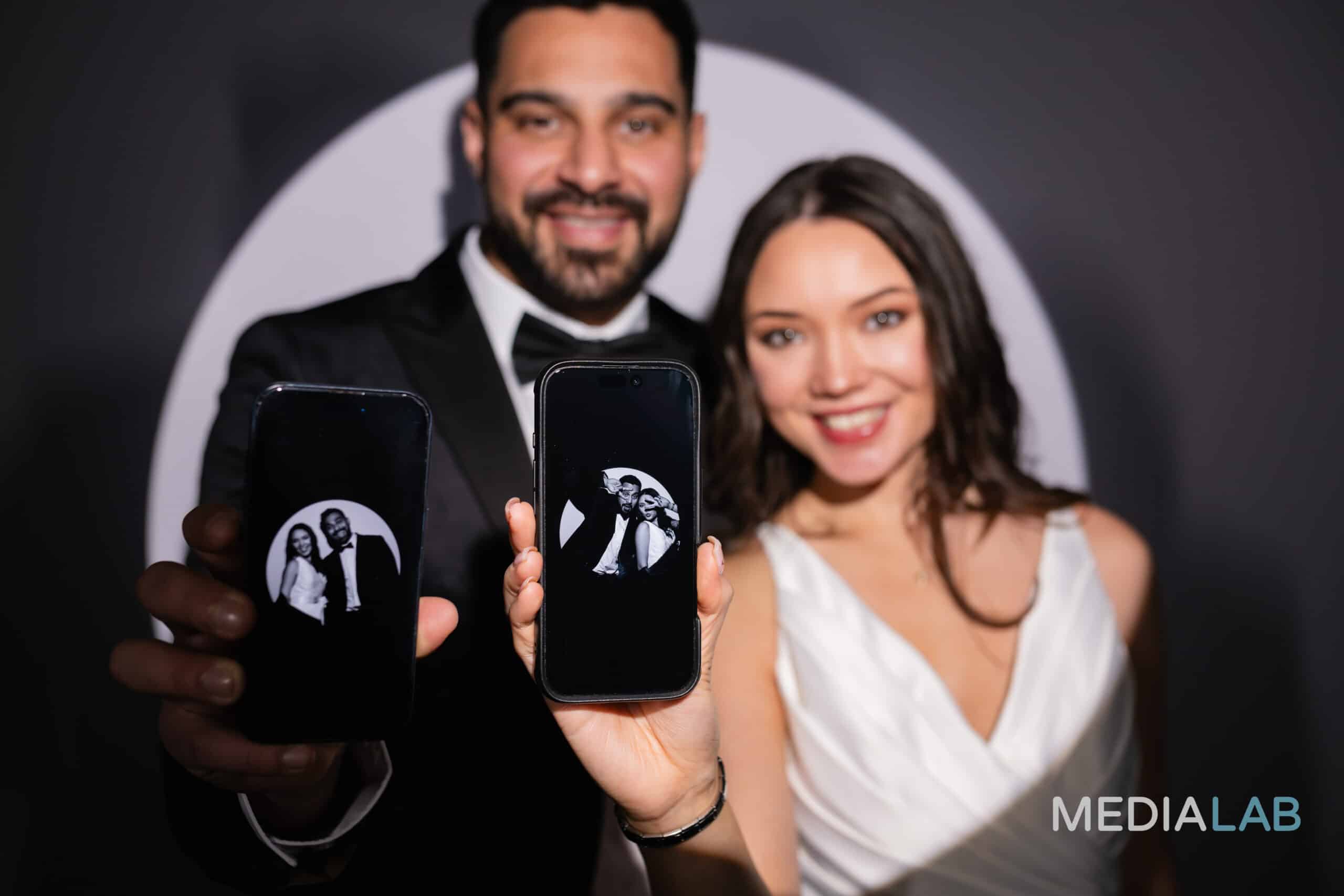 A group of people smiling and posing for a picture in a photo booth, holding props and looking at the camera.