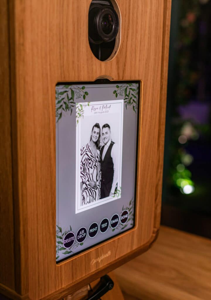 A group of people smiling and posing for a picture in a photo booth, holding various props including hats and a star-shaped sign.