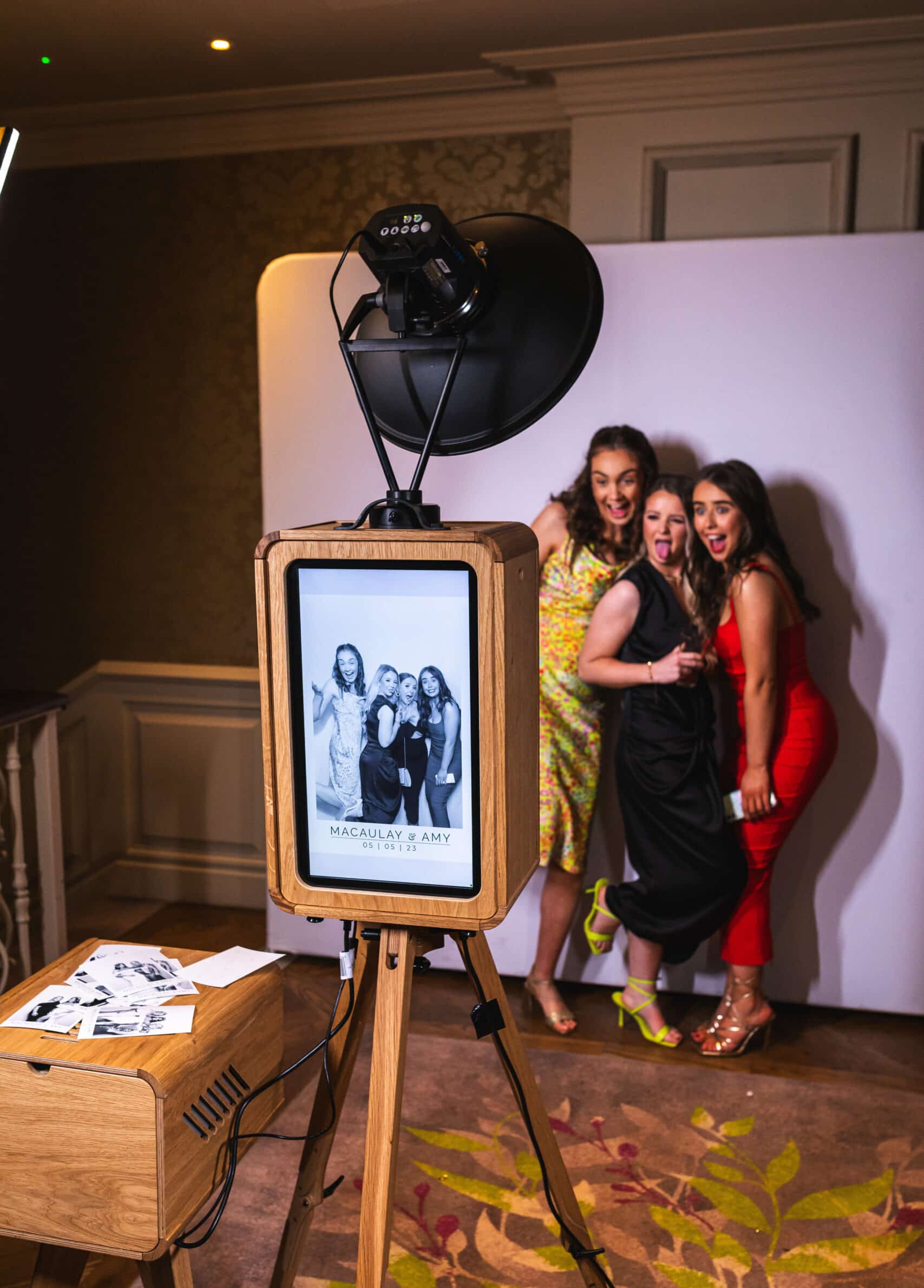 A group of people smiling and posing for a picture in a photo booth, holding various props.