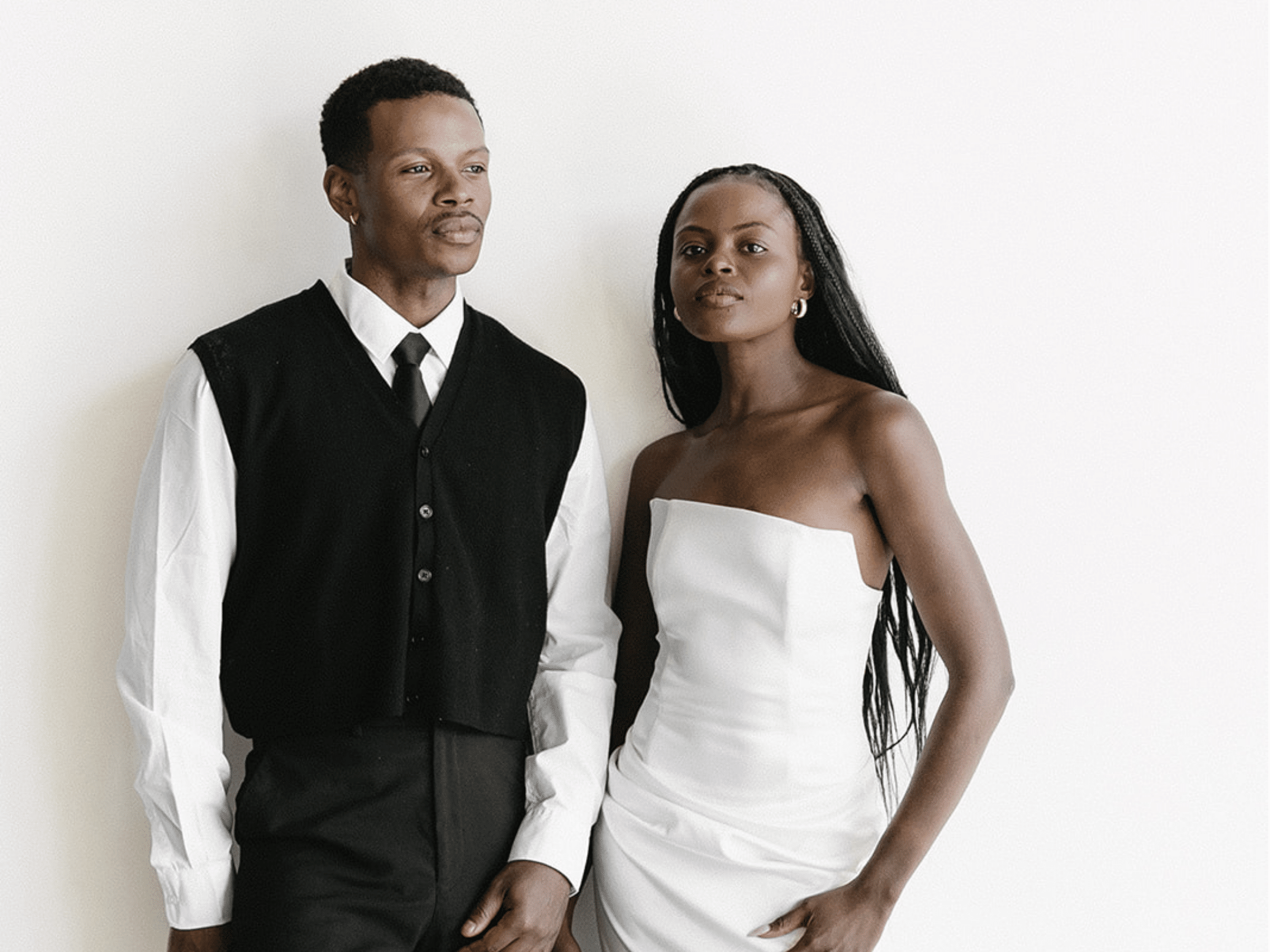 Bride and groom posing for the photo booth in front of a white backdrop