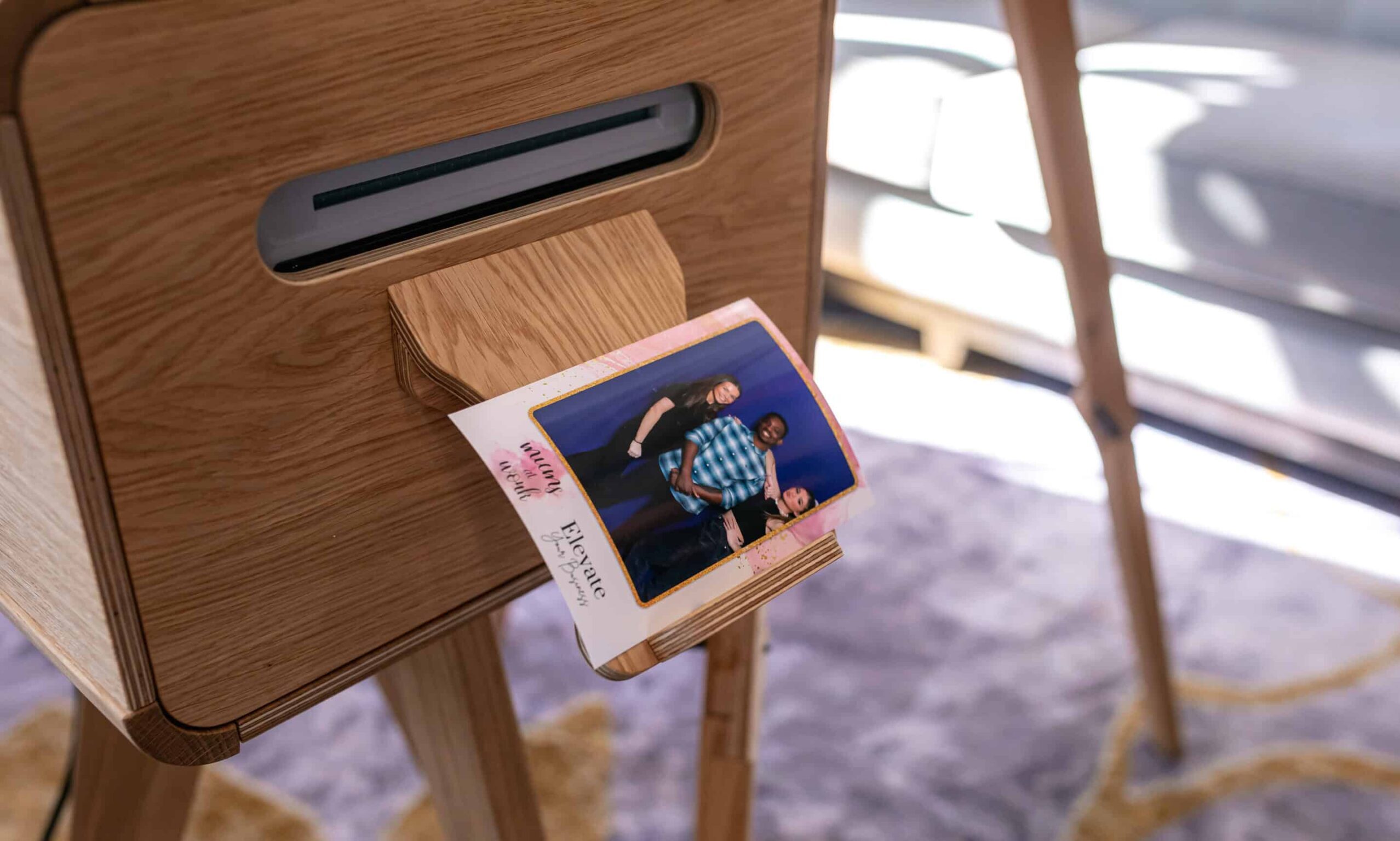 A couple smiling and posing for a picture in a photo booth at their wedding, with a custom backdrop featuring their names.