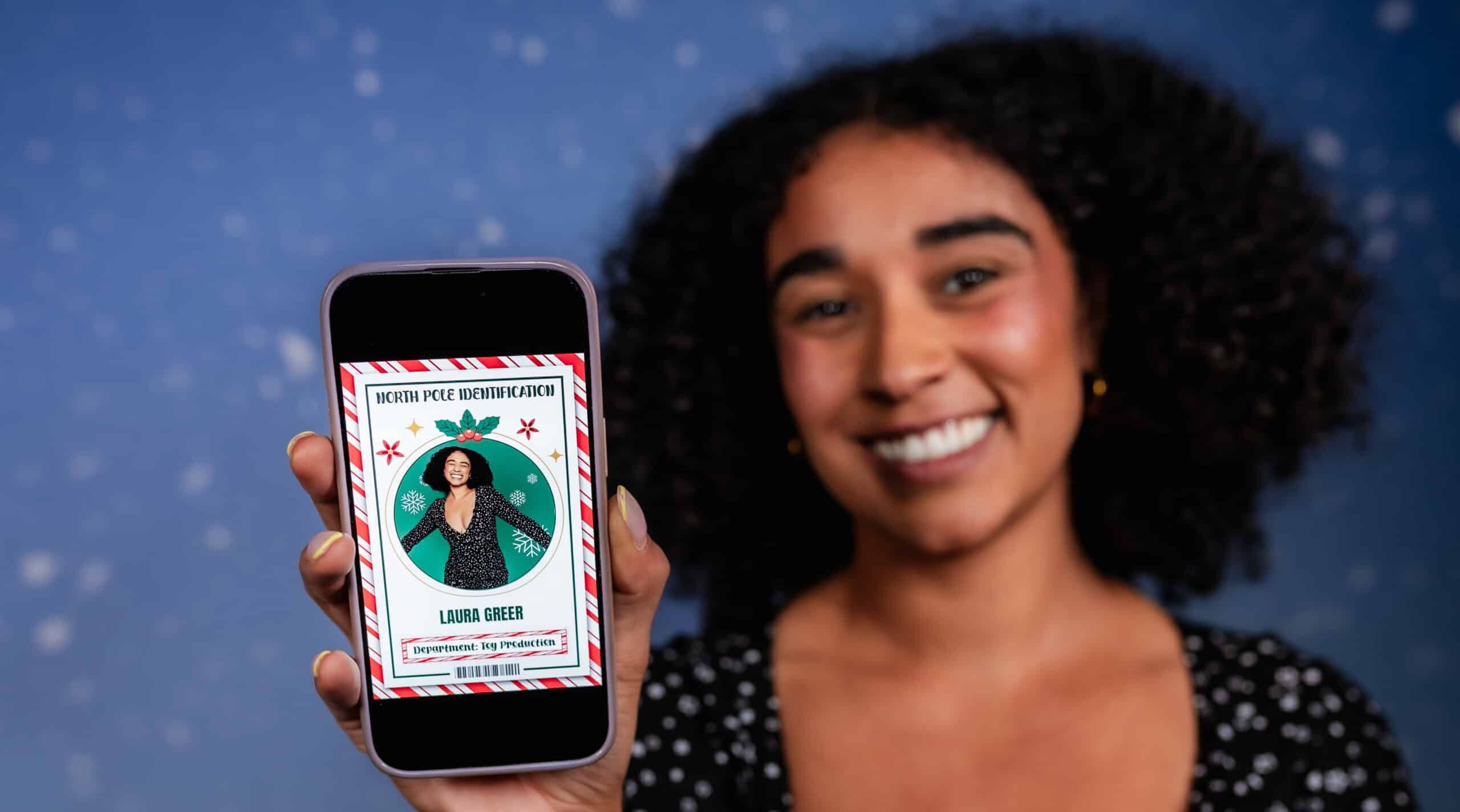 wo women in festive attire smiling and posing for a picture at a holiday-themed event, with one holding a cup.