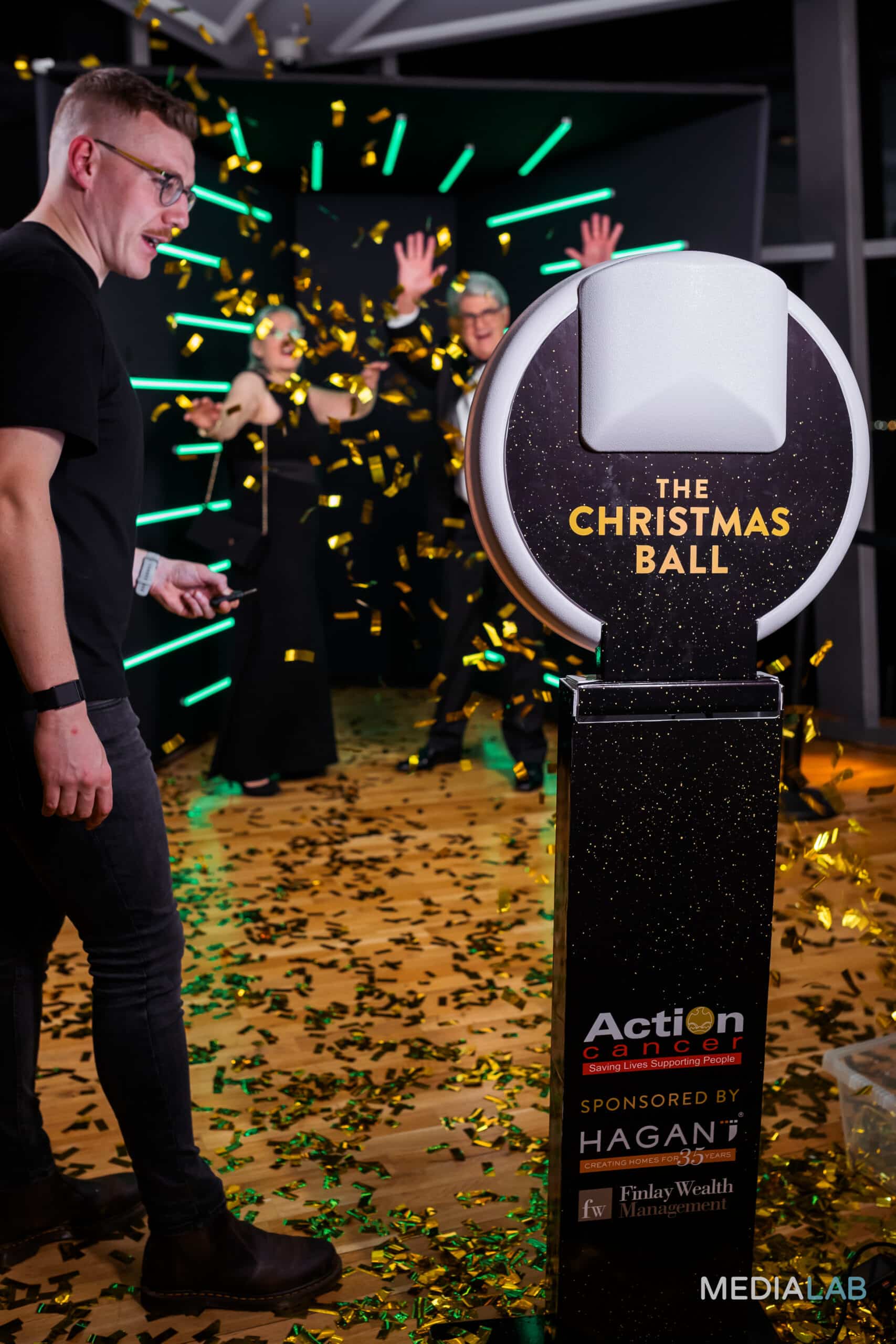 A group of people posing for a photo booth that creates a sleek, magazine-style cover, with a backdrop of vertical light bars.