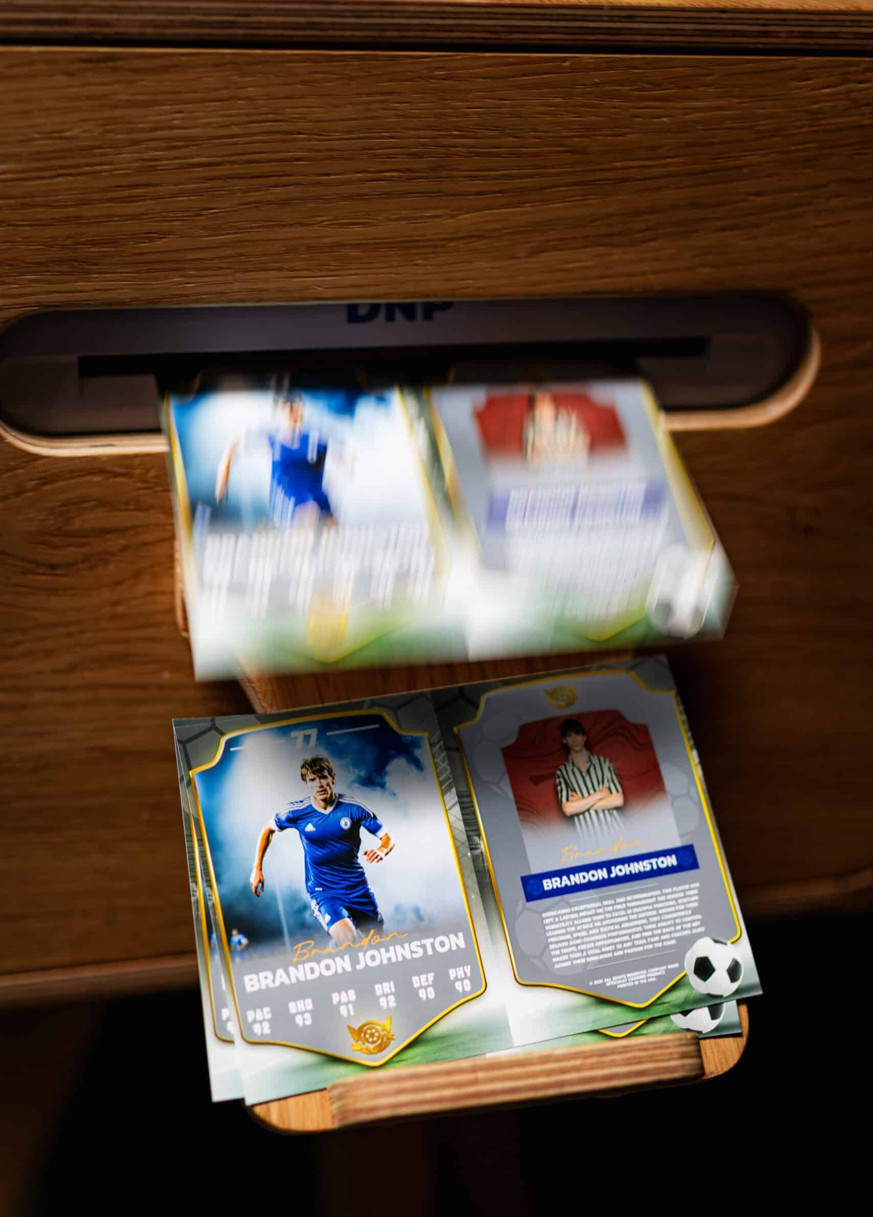 A group of people smiling at a camera inside a photo booth with a sleek, white background and cutsom trading cards..