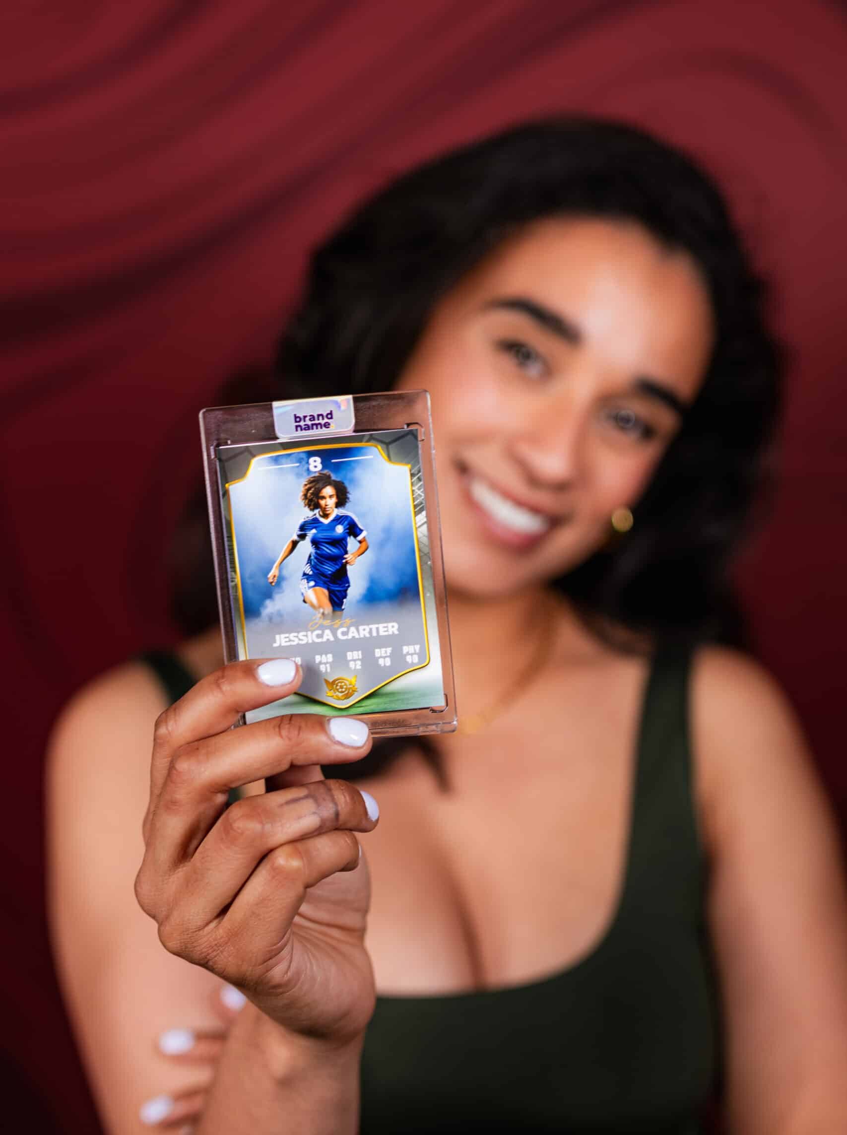 A woman in a black dress smiling with a drink in her hand while posing for a photo at a party or corporate event.