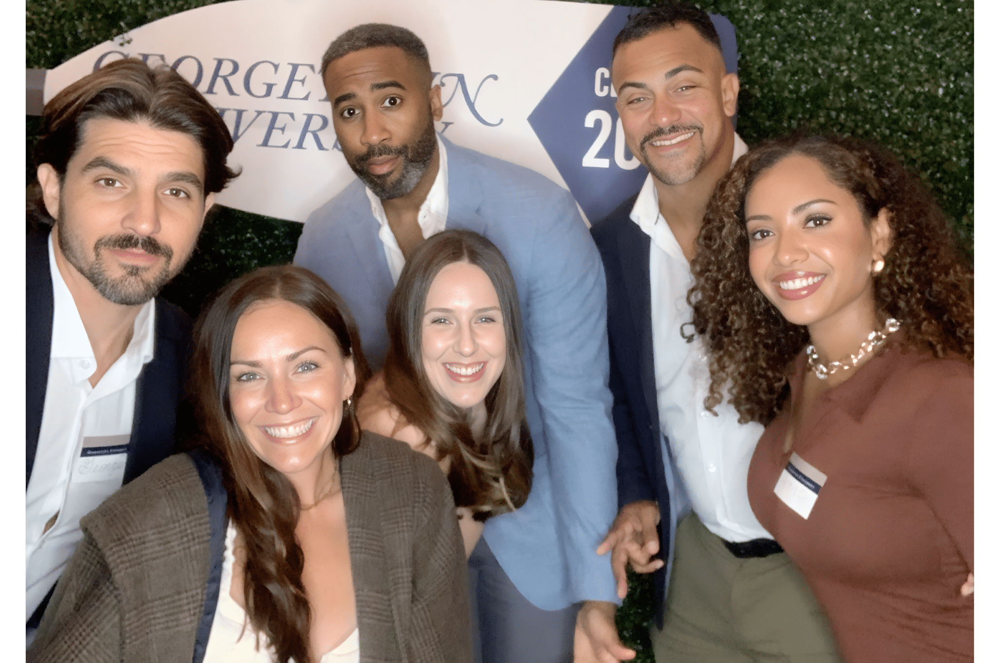Two women wearing graduation caps and smiling for a picture at a university reunion event.