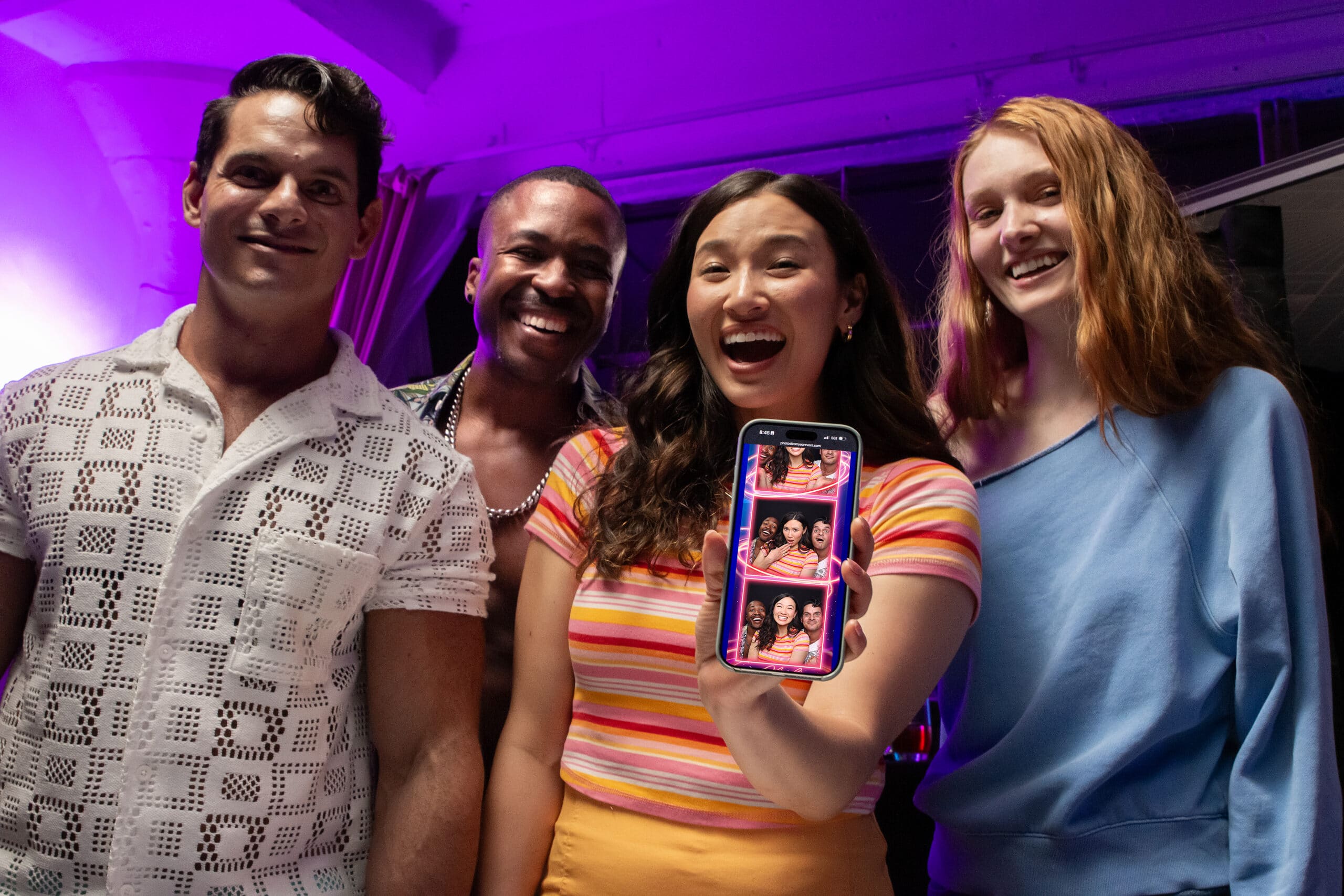 Two women smiling and posing for a picture inside an enclosed photo booth, with one pointing at the camera.