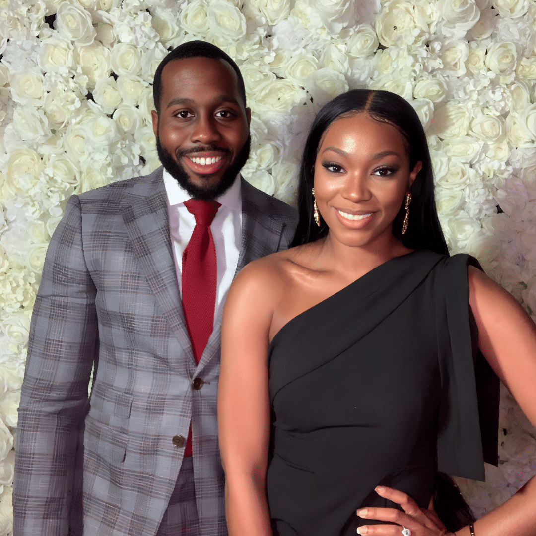 Smiling couple posing together in front of a floral backdrop, showcasing the engaging atmosphere of a photo booth experience at events.