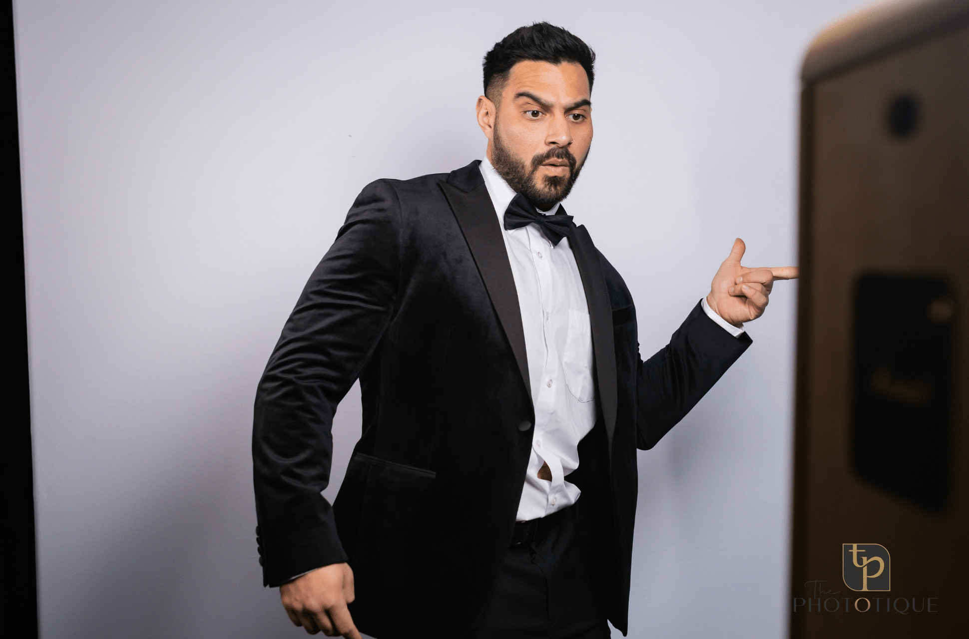 Man in a tuxedo interacting with a photo booth, showcasing a fun and engaging photo booth experience for events.