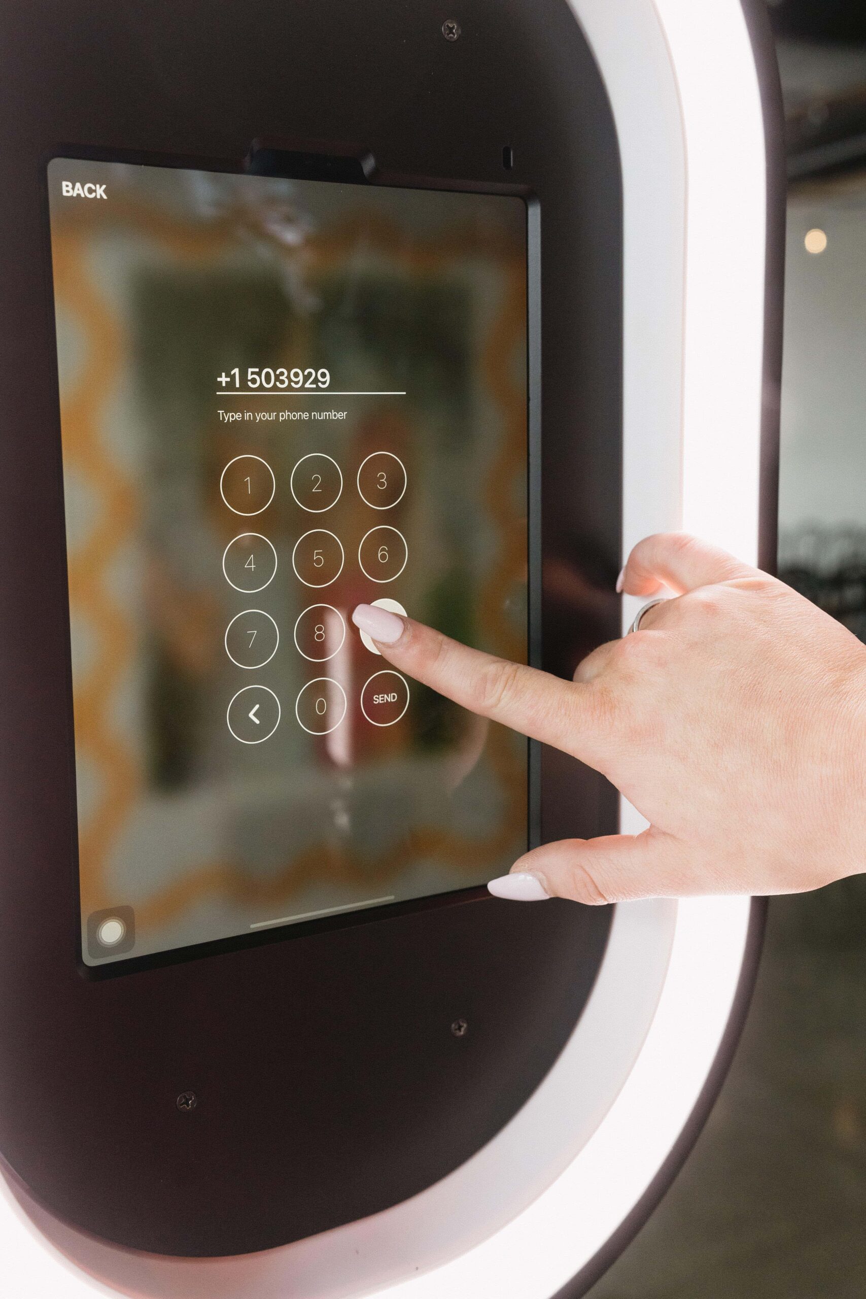 User entering phone number on digital screen of The Phototique photo booth, emphasizing interactive guest engagement and innovative technology for events.