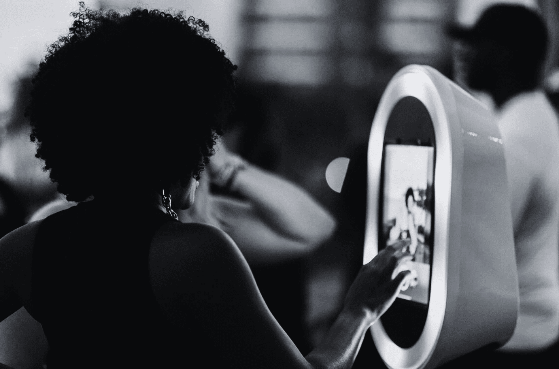 Woman interacting with a modern photo booth touchscreen at an event, capturing memorable moments.