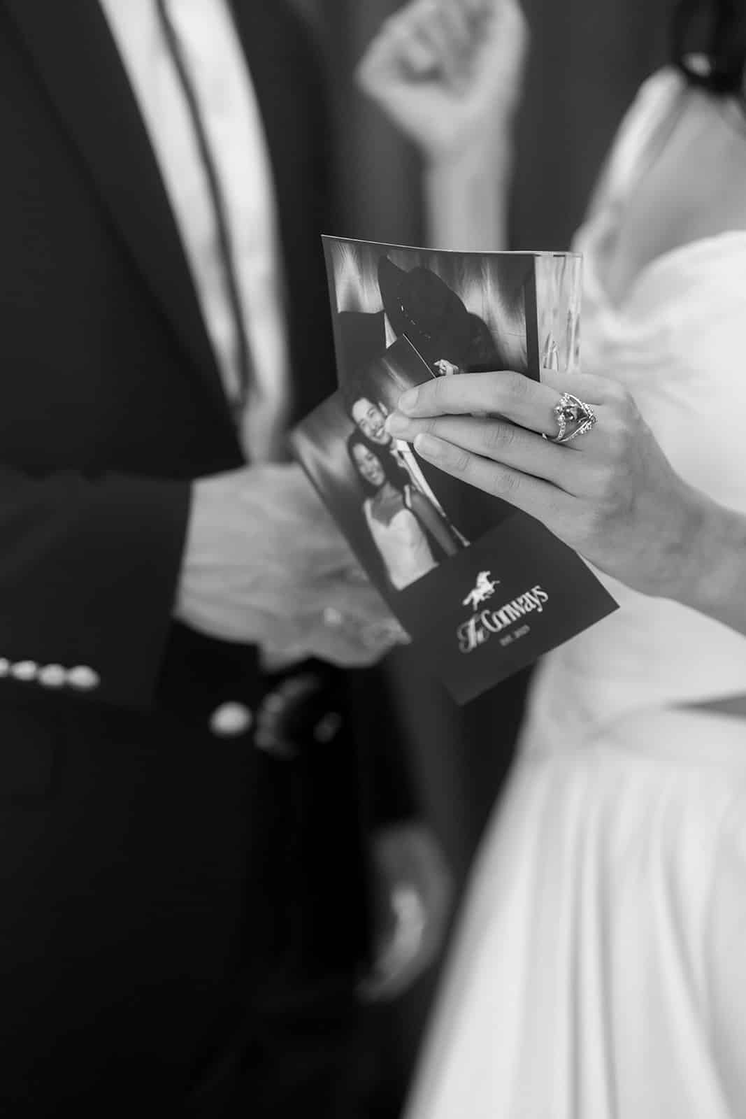 Couple holding photo booth prints featuring black-and-white images, showcasing moments from their event, emphasizing the personalized photo booth experience offered by The Phototique.