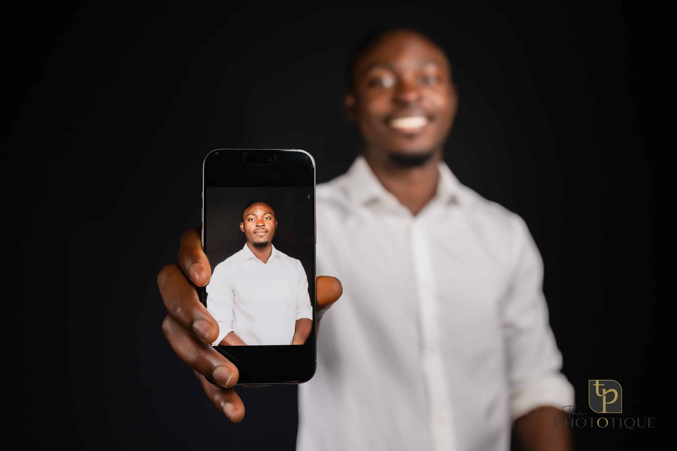 Man holding smartphone displaying a professional headshot, showcasing The Phototique's headshot booth service for corporate events.