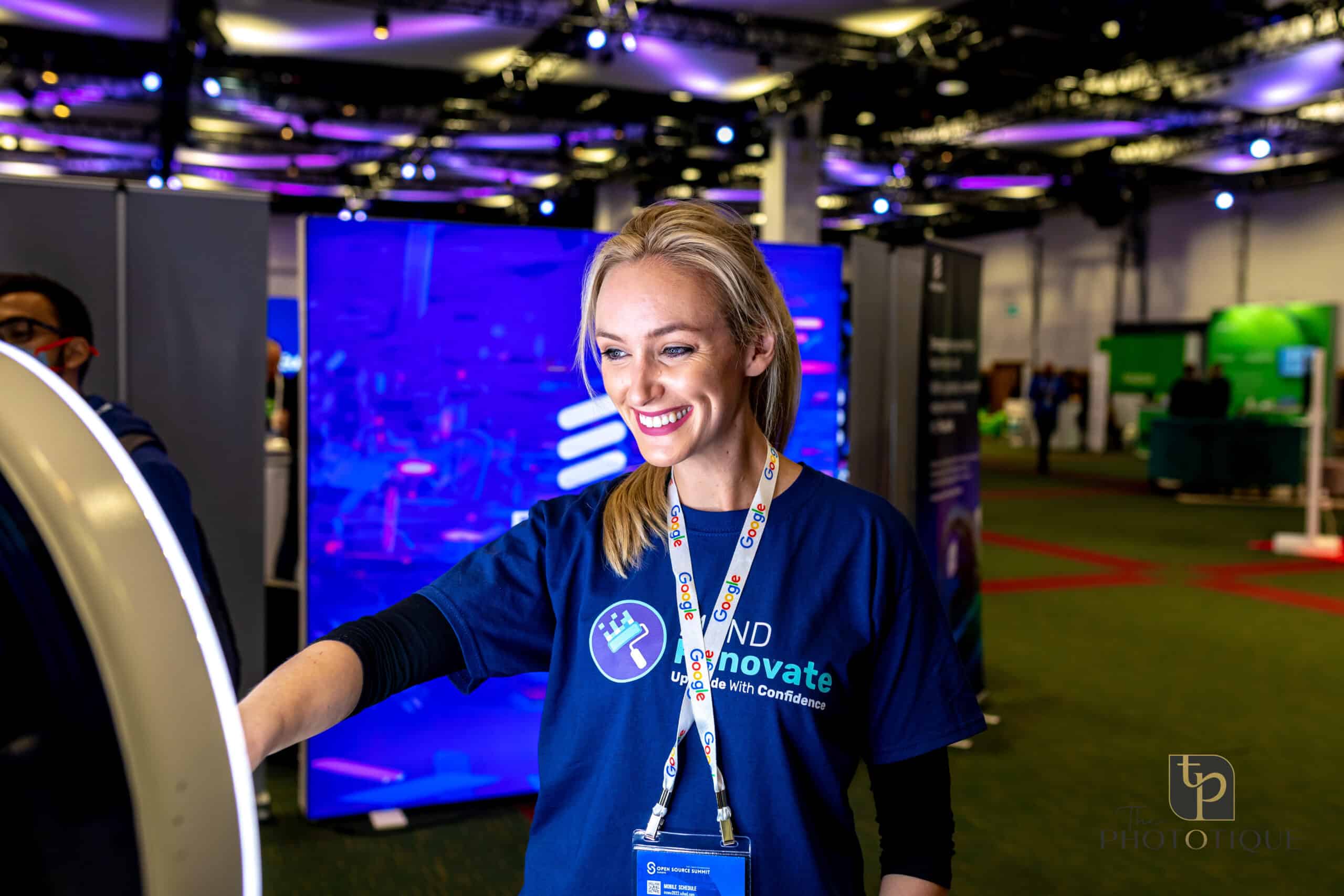 Smiling event attendant interacting with a luxury photo booth, showcasing high-tech features in a vibrant conference setting, emphasizing engagement and personalization for upscale events.