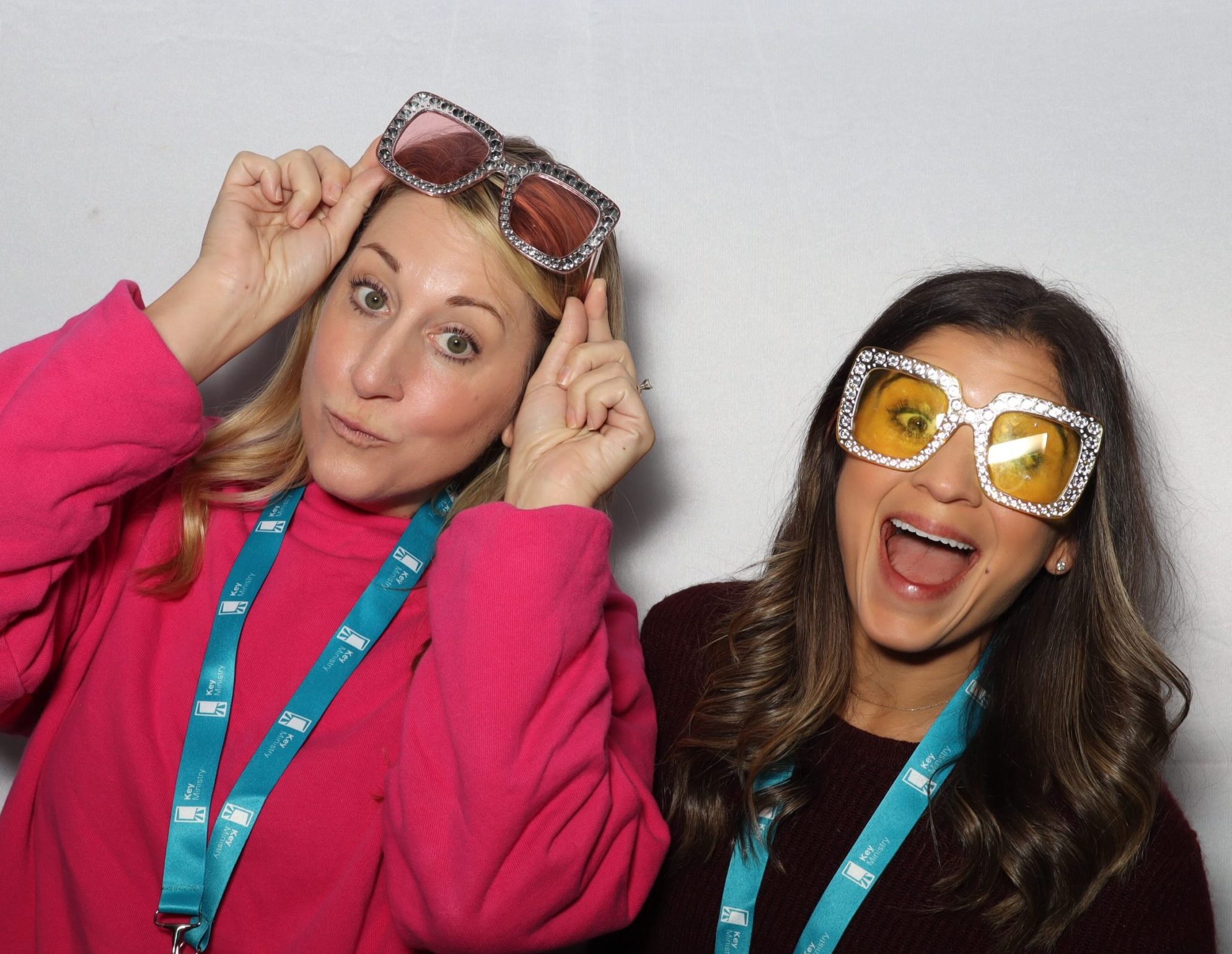 two women pose in front of a white backdrop for the photo booth at a dc conference